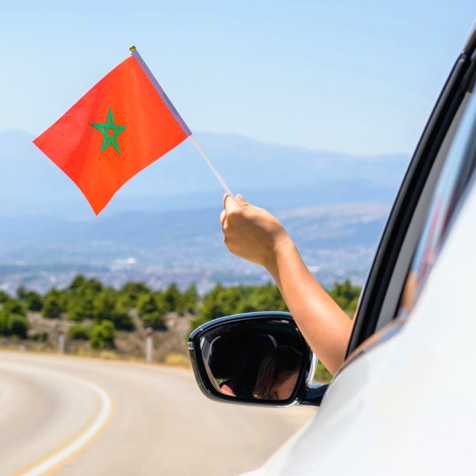 Questa immagine mostra una bandierina marocchina che viene sventolata fuori da un&#39;auto.