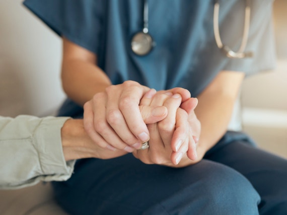 Operatore sanitario che stringe la mano di una paziente