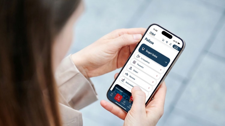 Donna tiene in mano uno smartphone mostrando l&#39;interfaccia dell&#39;app Unipol nella sezione Polizze e servizi.