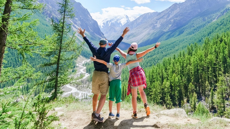 questa immagine mostra una famiglia durante un trekking in montagna mentre posa guardando il panorama