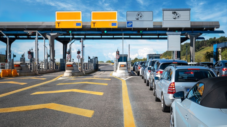 Coda di auto al casello autostradale nelle corsie per il pagamento manuale, mentre le corsie di telepedaggio sono libere.