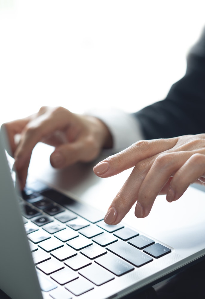 Primo piano di mani femminili che digitano sulla tastiera di un computer portatile.